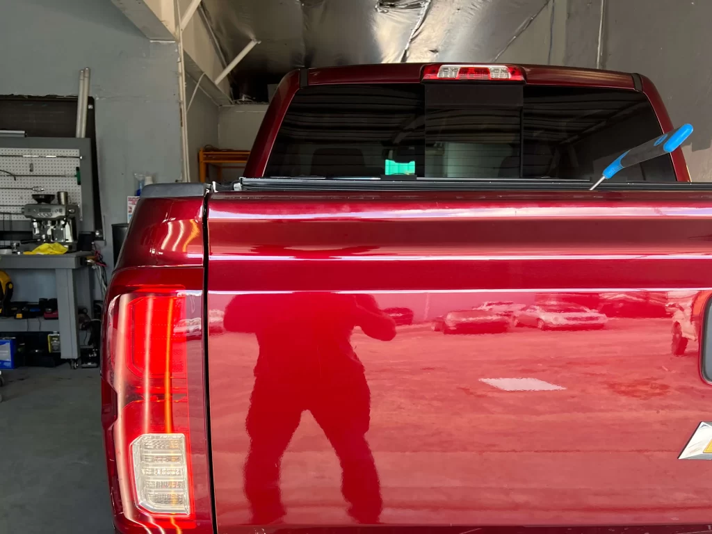 The shiny rear of a cherry red Chevrolet Silverado inside a garage.